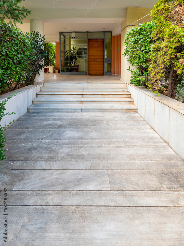 Obraz premium A contemporary residential apartment building main entrance marble stairway and a wooden door. Athens, Greece.