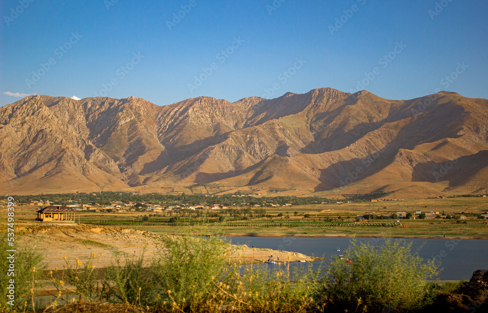 Grass pasture with lake and background mountains