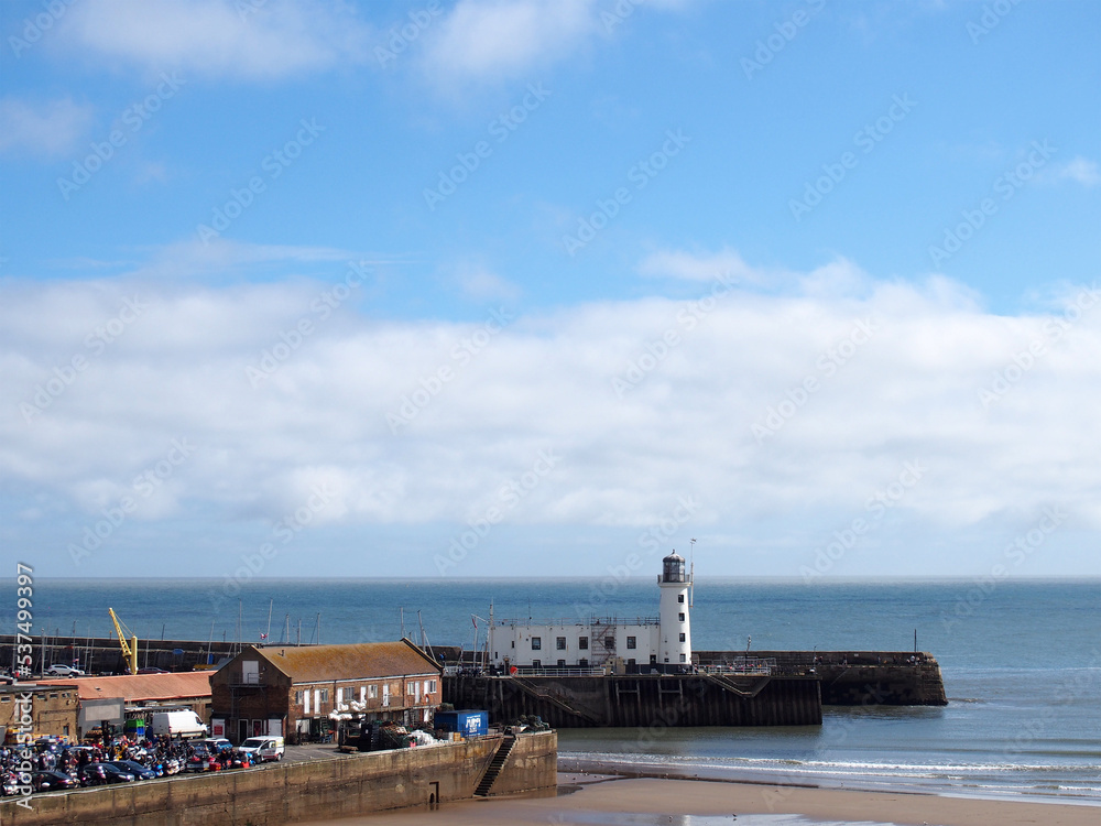 view of scarborough harbour and lighthouse on a sunlit summer day with blue sky and sea