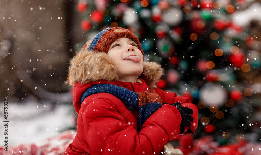 Child catch snowflakes with tongue. Christmas and New Year tree cozy. Concept of childhood and happiness. New Year Christmas holiday. Happy kid playing with snow outdoor. Holidays winter season. Child catch snowflakes with tongue. Christmas and New Year tree cozy. Concept of childhood and happiness. New Year Christmas holiday. Happy kid playing with snow outdoor. Holidays winter season.