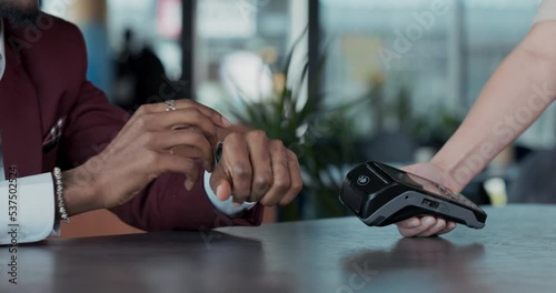 Close-up of a man's hand paying with a smart watch for an order at a restaurant. Successful transaction using the terminal.