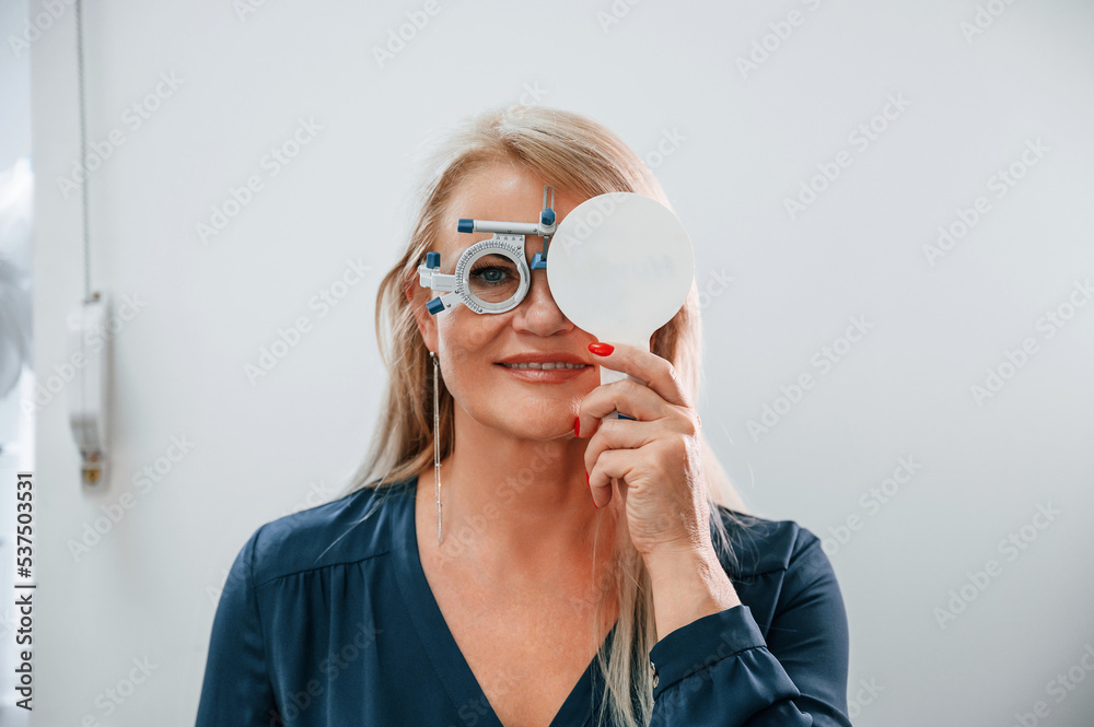 Covering the eye. Woman testing her sight by using special glasses. Covering the eye. Woman testing her sight by using special glasses.