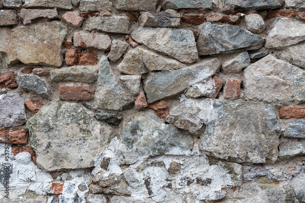 Close up variety of red bricks and large, uneven stones on an old, chaotic wall. Rough, urban, grungy texture with crooked and different shaped rocks for backgrounds. Graphic design element. Close up variety of red bricks and large, uneven stones on an old, chaotic wall. Rough, urban, grungy texture with crooked and different shaped rocks for backgrounds. Graphic design element.