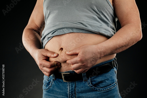 a fat man checking his weight on a black background.
