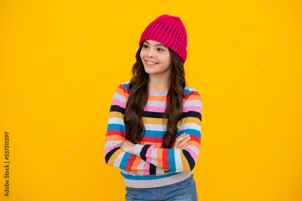 Modern teen girl wearing sweater and knitted hat on isolated yellow background. Happy teenager, positive and smiling emotions of teen girl. Modern teen girl wearing sweater and knitted hat on isolated yellow background. Happy teenager, positive and smiling emotions of teen girl.