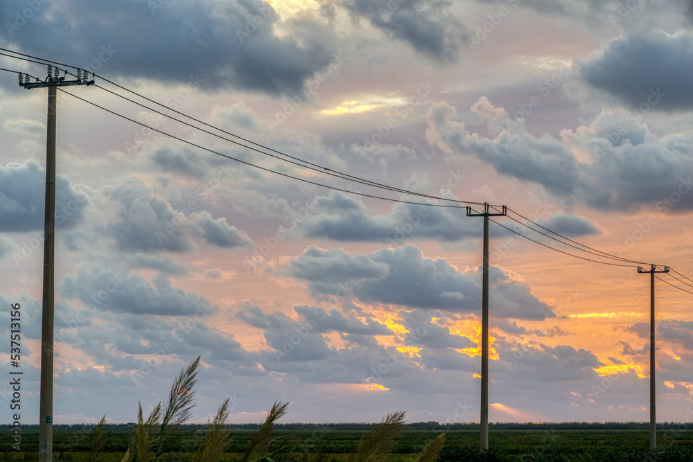 electricity poles under clouds in sunrise