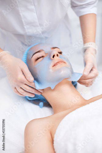 beautician removing mask from face of beautiful woman