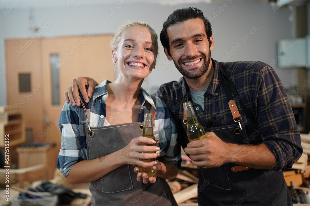 Happy Couple Carpenters have celeabate with a drink bottle after work of Assembling Furniture, Small business in wood DIY workplace office background
