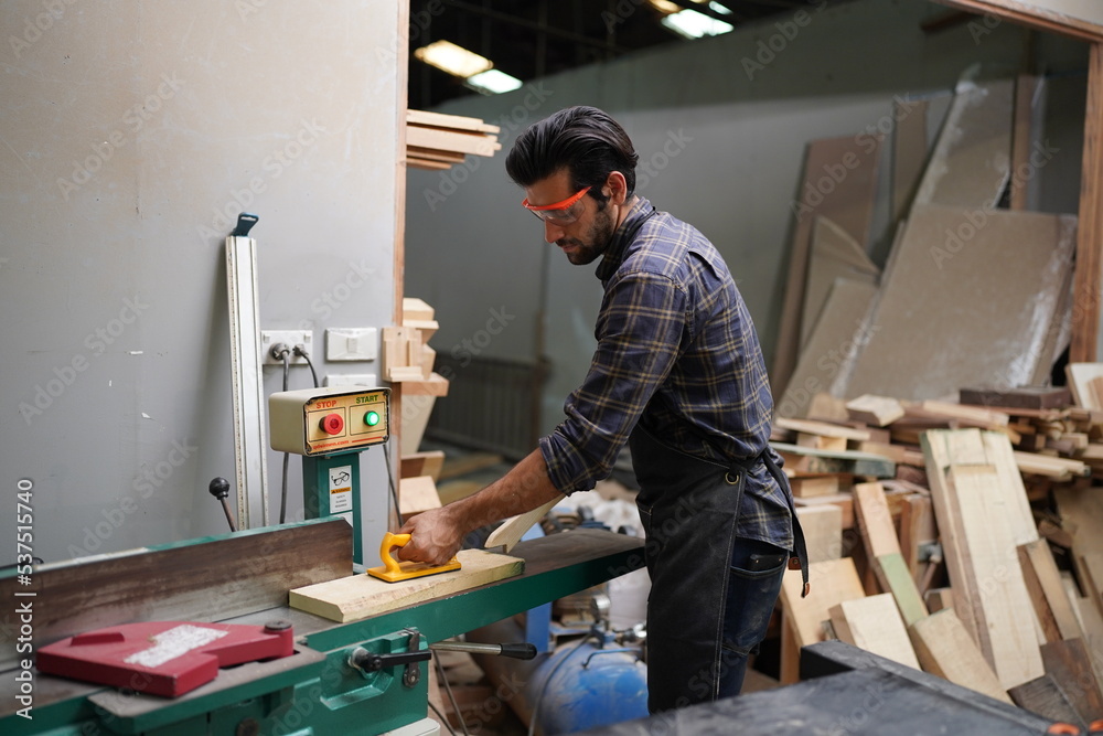Contemporary Carpenter Working, Portrait of modern carpenter making wood furniture while working in joinery lit by sunlight with factory background on small business concept, copy space Contemporary Carpenter Working, Portrait of modern carpenter making wood furniture while working in joinery lit by sunlight with factory background on small business concept, copy space