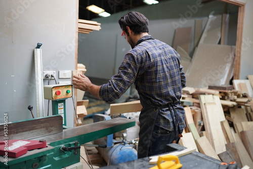 Contemporary Carpenter Working, Portrait of modern carpenter making wood furniture while working in joinery lit by sunlight with factory background on small business concept, copy space © FotoArtist