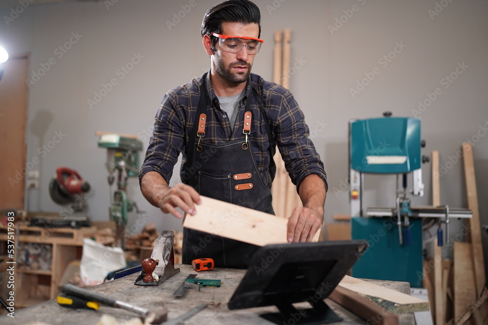 Contemporary Carpenter Working, Portrait of modern carpenter making wood furniture while working in joinery lit by sunlight with factory background on small business concept, copy space Contemporary Carpenter Working, Portrait of modern carpenter making wood furniture while working in joinery lit by sunlight with factory background on small business concept, copy space