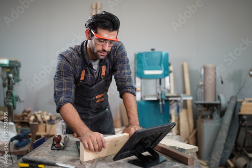 Contemporary Carpenter Working, Portrait of modern carpenter making wood furniture while working in joinery lit by sunlight with factory background on small business concept, copy space © FotoArtist