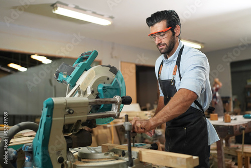 Contemporary Carpenter Working, Portrait of modern carpenter making wood furniture while working in joinery lit by sunlight with factory background on small business concept, copy space