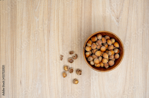 Hazelnuts in a bowl with few cracked next to it on the table. Flat lay.