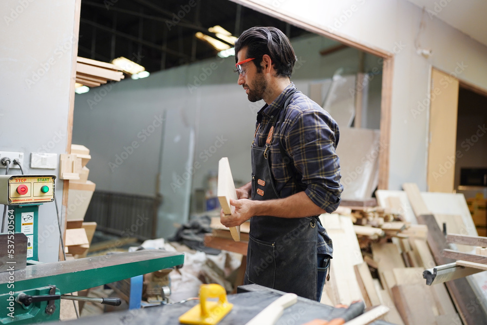 Contemporary Carpenter Working, Portrait of modern carpenter making wood furniture while working in joinery lit by sunlight with factory background on small business concept, copy space Contemporary Carpenter Working, Portrait of modern carpenter making wood furniture while working in joinery lit by sunlight with factory background on small business concept, copy space