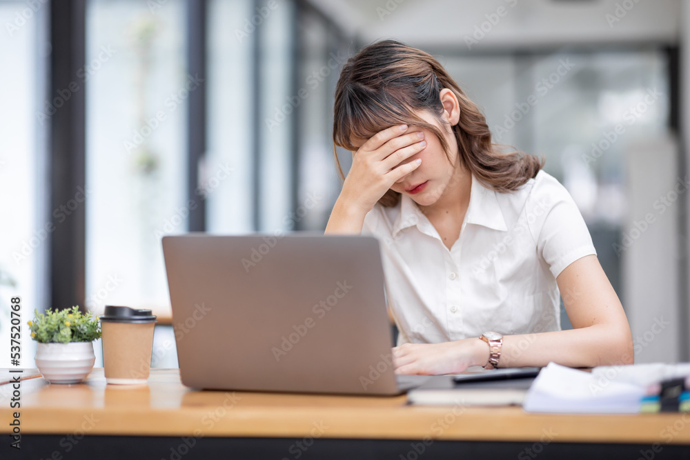 Young Business Asian women are stressed while working on laptop, Tired asian businesswoman with headache at office, feeling sick at work copy space in workplace an home office. Young Business Asian women are stressed while working on laptop, Tired asian businesswoman with headache at office, feeling sick at work copy space in workplace an home office.