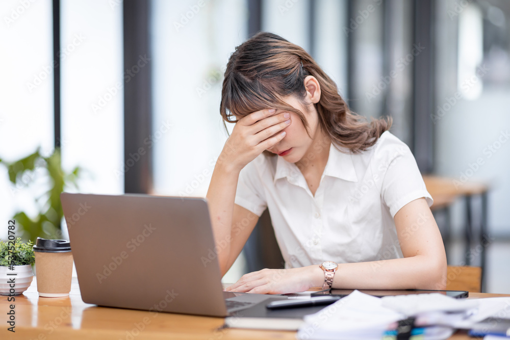Young Business Asian women are stressed while working on laptop, Tired asian businesswoman with headache at office, feeling sick at work copy space in workplace an home office. Young Business Asian women are stressed while working on laptop, Tired asian businesswoman with headache at office, feeling sick at work copy space in workplace an home office.