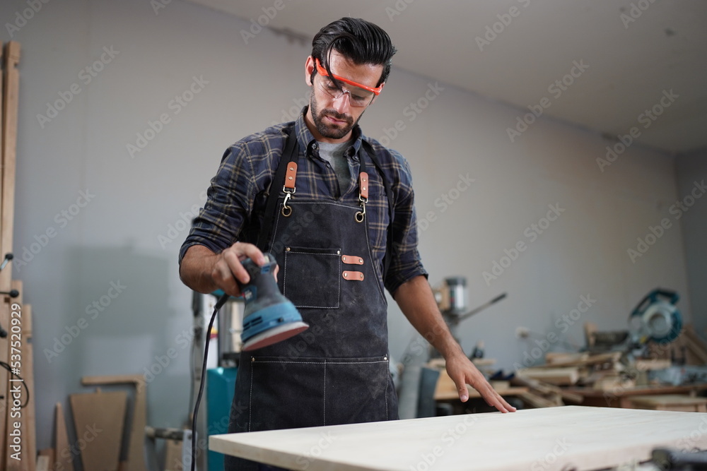Contemporary Carpenter Working, Portrait of modern carpenter making wood furniture while working in joinery lit by sunlight with factory background on small business concept, copy space Contemporary Carpenter Working, Portrait of modern carpenter making wood furniture while working in joinery lit by sunlight with factory background on small business concept, copy space