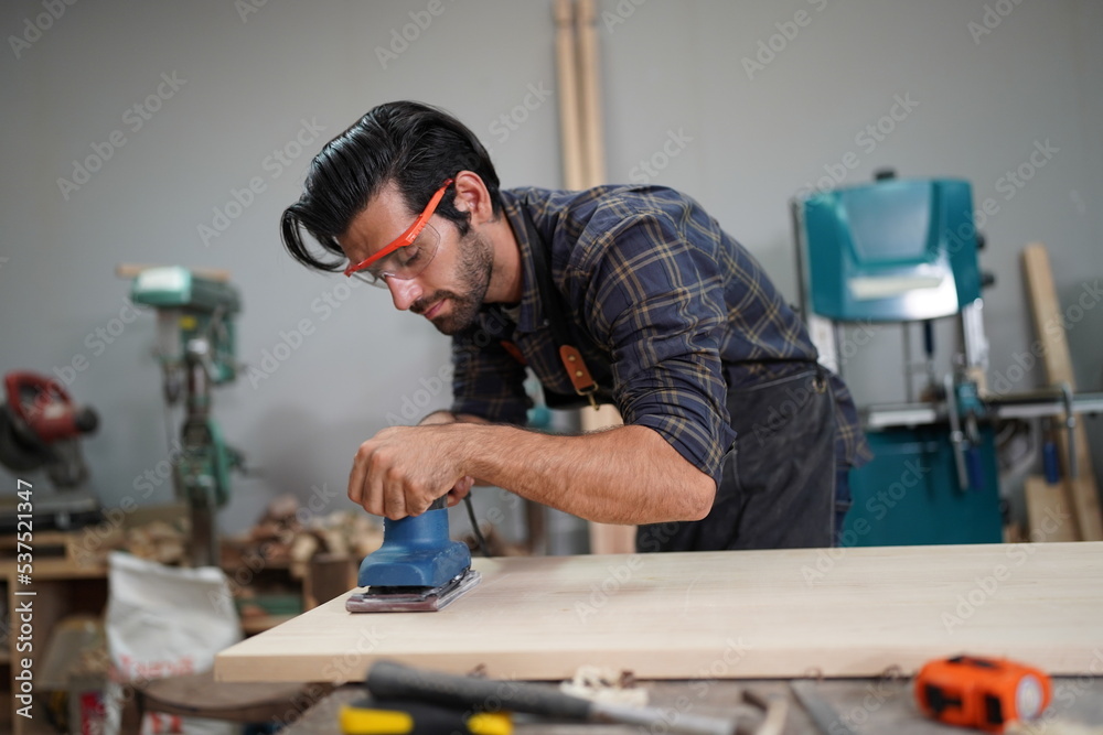 Contemporary Carpenter Working, Portrait of modern carpenter making wood furniture while working in joinery lit by sunlight with factory background on small business concept, copy space