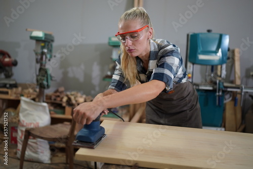 Contemporary Carpenter Working, Portrait of modern carpenter making wood furniture while working in joinery lit by sunlight with factory background on small business concept, copy space © FotoArtist