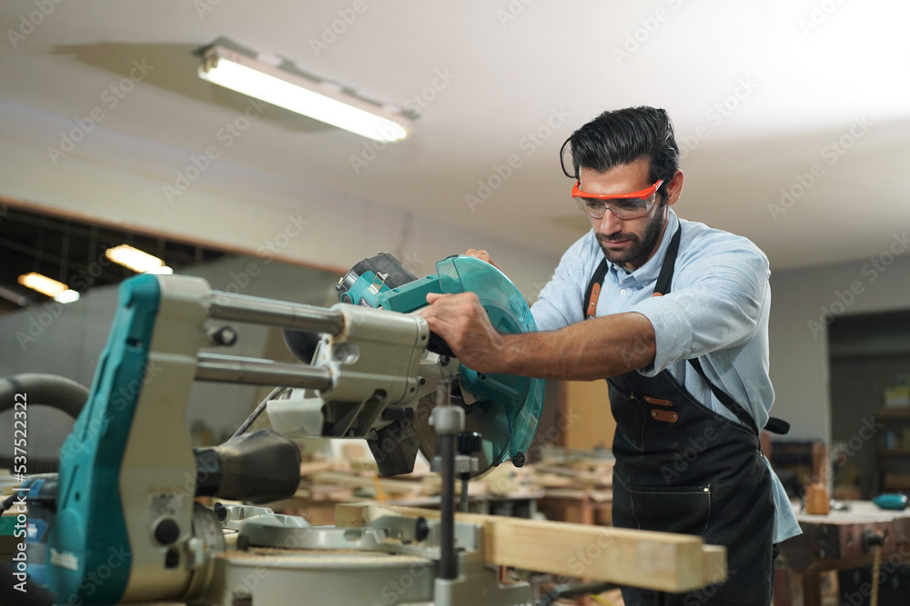 Contemporary Carpenter Working, Portrait of modern carpenter making wood furniture while working in joinery lit by sunlight with factory background on small business concept, copy space