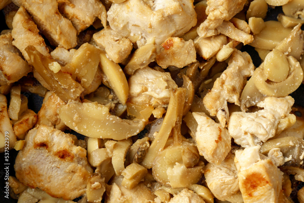 Chopped chicken fillet with mushroom fried on frying pan. Cooking process close up. Chopped chicken fillet with mushroom fried on frying pan. Cooking process close up.