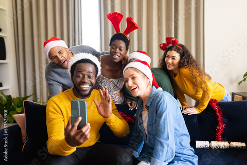 Image of happy diverse friends celebrating christmas at home making smartphone video call © wavebreak3