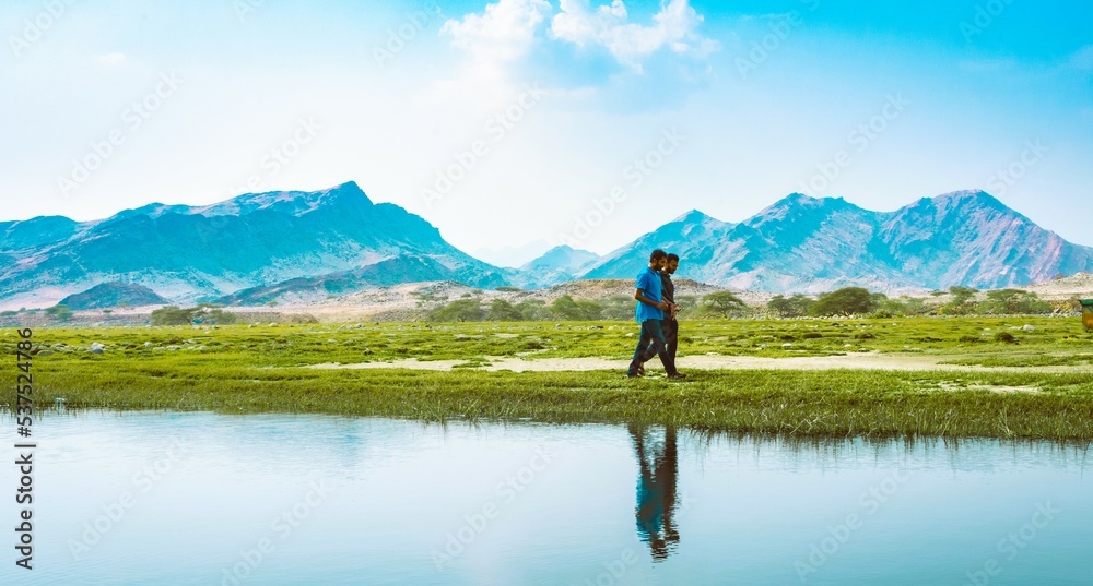 People walking by a lake in a valley