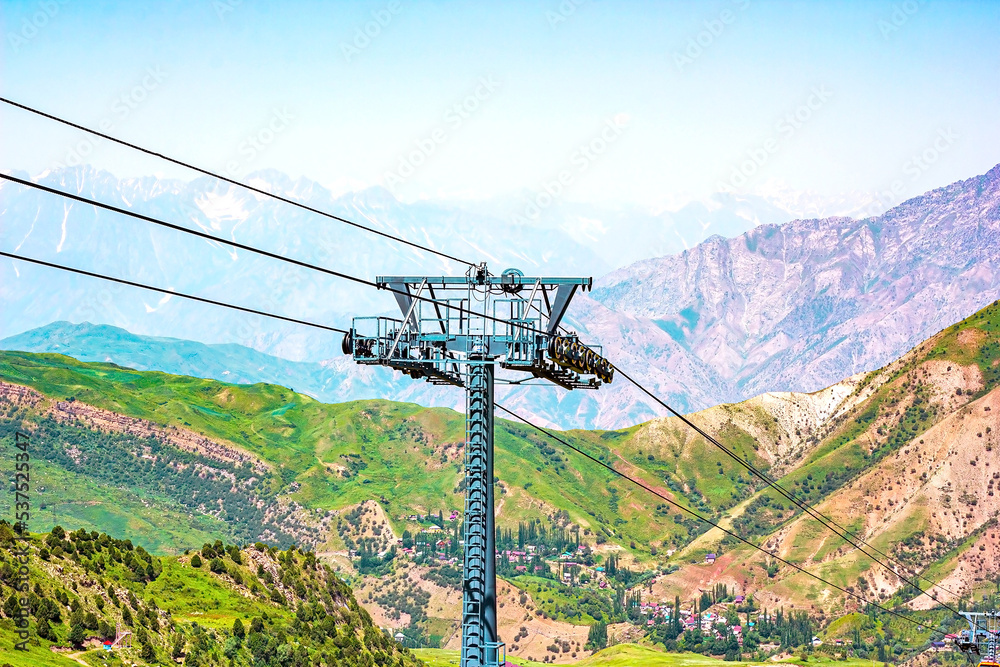 Сableway for tourists on green mountains and blue sky background in summer.