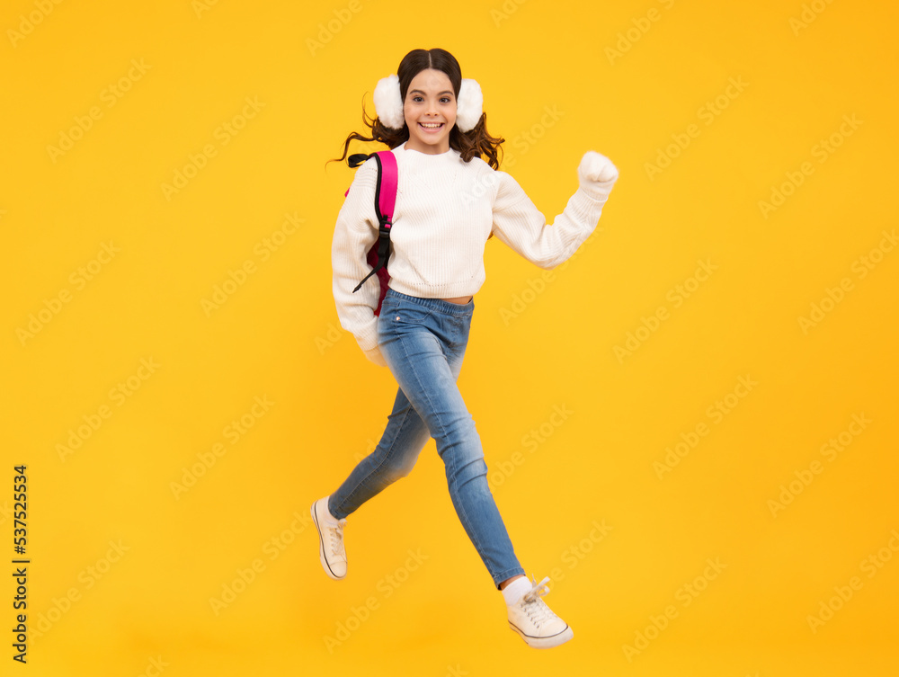 Schoolgirl child student with backpack and warn hat, isolated yellow background. Learning and knowledge education concept.