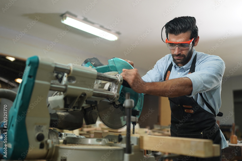 Contemporary Carpenter Working, Portrait of modern carpenter making wood furniture while working in joinery lit by sunlight with factory background on small business concept, copy space Contemporary Carpenter Working, Portrait of modern carpenter making wood furniture while working in joinery lit by sunlight with factory background on small business concept, copy space