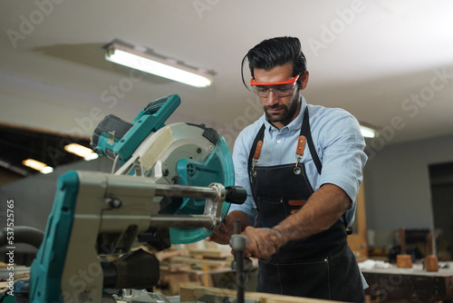 Contemporary Carpenter Working, Portrait of modern carpenter making wood furniture while working in joinery lit by sunlight with factory background on small business concept, copy space