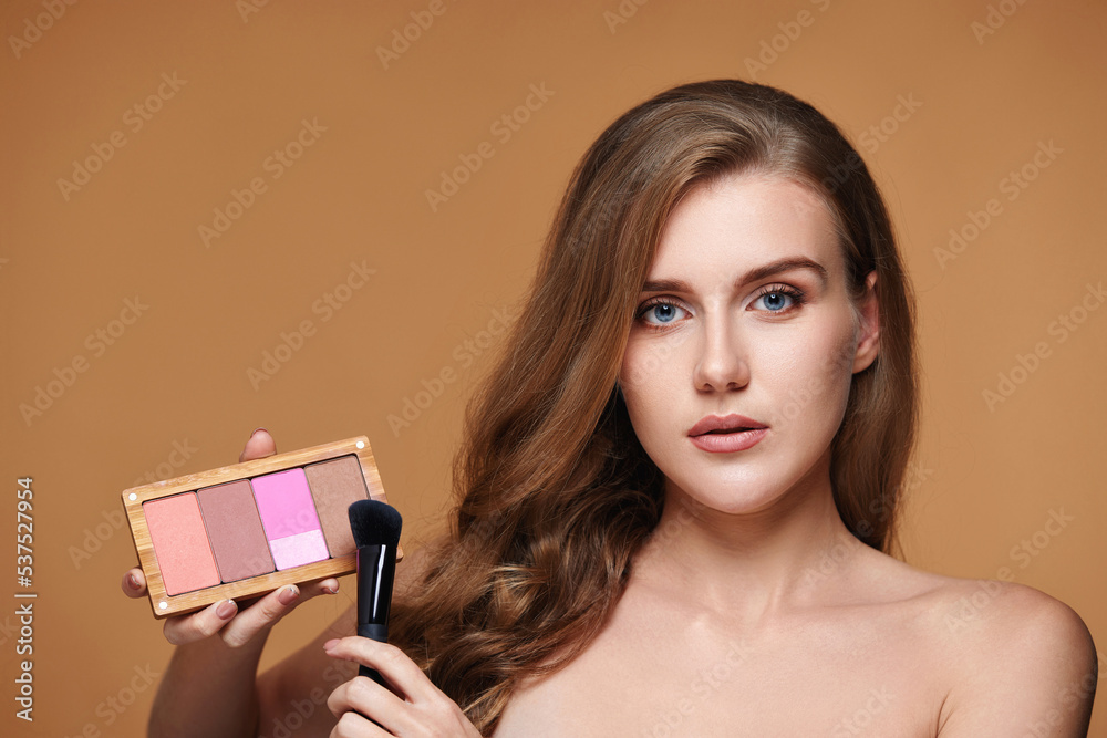 woman applying blush on cheekbone with make-up brush woman applying blush on cheekbone with make-up brush