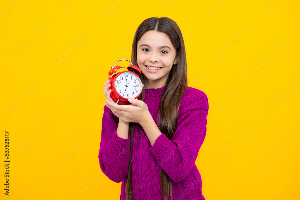 Teen girl holding clock over yellow background. Early morning, daily schedule. Child checking time. do not be late. Punctual kid with alarm. Deadline time. Teen girl holding clock over yellow background. Early morning, daily schedule. Child checking time. do not be late. Punctual kid with alarm. Deadline time.
