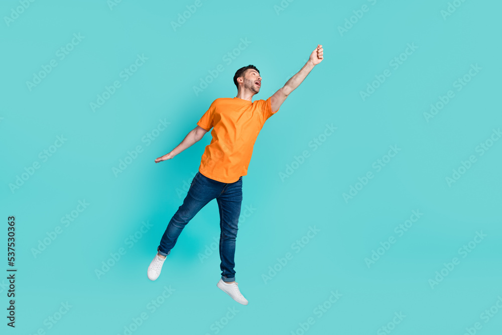 Full body photo of positive person raise arm hold empty space banner look up wear orange clothes jeans isolated on cyan color background