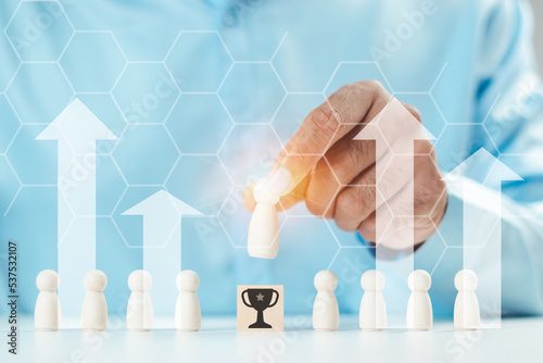 A businessman's hand selects a wooden figures that stood out from the crowd. Trophy icon and arrow pointing up. human resource concept leadership teamwork Business and finance. Wooden blocks.