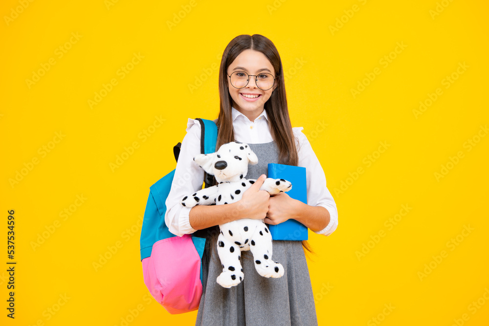 Back to school. Teenager schoolgirl hold book with toy ready to learn. School children on isolated yellow studio background. Back to school. Teenager schoolgirl hold book with toy ready to learn. School children on isolated yellow studio background.