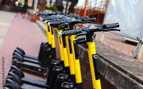 Parking of modern electric scooters on city streets. Modern black and yellow electric scooters parked on the street of a modern city