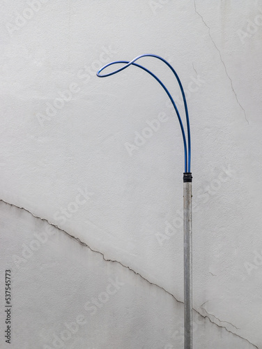Life saving hook or Life hook front of white concrete wall near swimming pool, Life hook is a life saving device for used to help swimmers in an emergency situation. Has space on left side for creativ