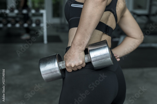 Asian woman who is determined to lose weight at fitness gym and exercising with dumbbells.