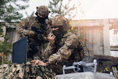 Mobile military base, soldier engineer transmits aerial pictures and data from drone to artillery. Concept of smart war by robots