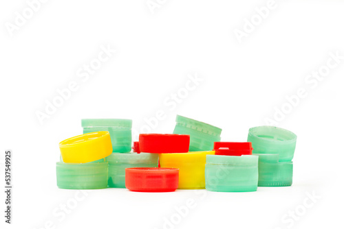 Composición con tapas de botellas de plástico de colores sobre un fondo blanco liso y aislado. Vista de frente y de cerca. Copy space