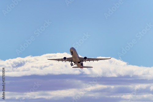 Large generic plane taking height towards the clouds after taking off from the ground.