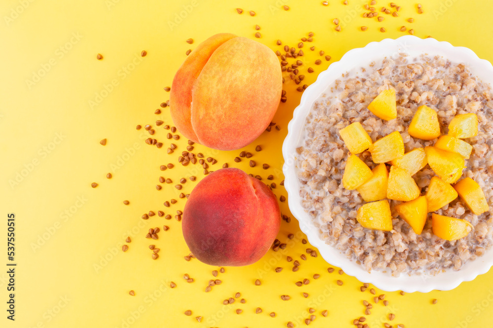 Φωτογραφία Buckwheat porridge with milk and peach in a white bowl (plate) on an orange background