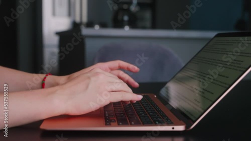 Camera slides around female freelancer's hands typing on laptop keyboard in slow motion. Business woman working at office with internet. Girl working remotely from home. Slow motion tracking shot. photo