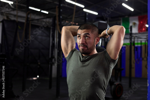 close up of a latino athlete doing triceps exercise in a gym with a dumbbell