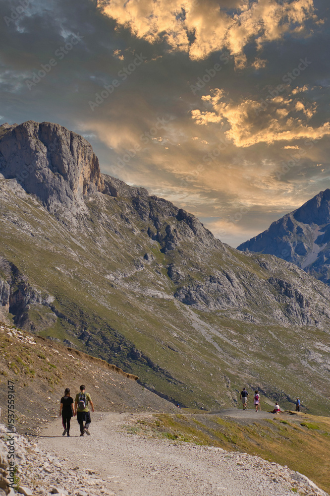 Senderismo entre montañas al atardecer. Gente caminando en un valle