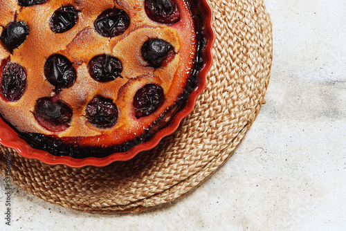 Fresh homemade plum pie in ceramic form on grey concrete background. Plum Skillet Cake. Delicious summer dessert. Selective focus