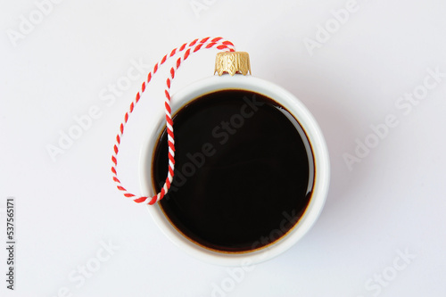 White cup of black espresso coffee decorated as Christmas ball. Close up, white background. New Year holiday concept