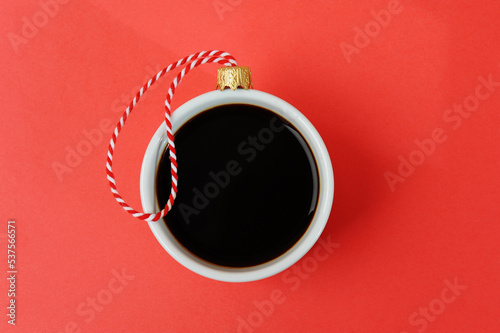 White cup of black espresso coffee decorated as Christmas ball. Close up, red background. New Year holiday concept